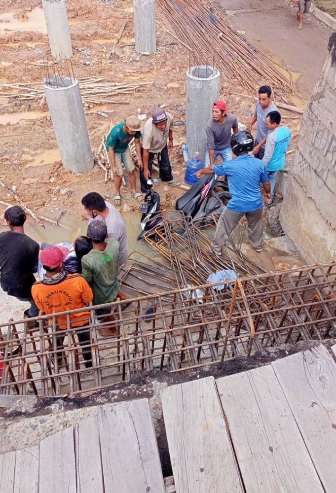 Warga dan pekerja proyek rehabilitasi jembatan mengevakuasi pengendara yang terjatuh. (istimewa)
